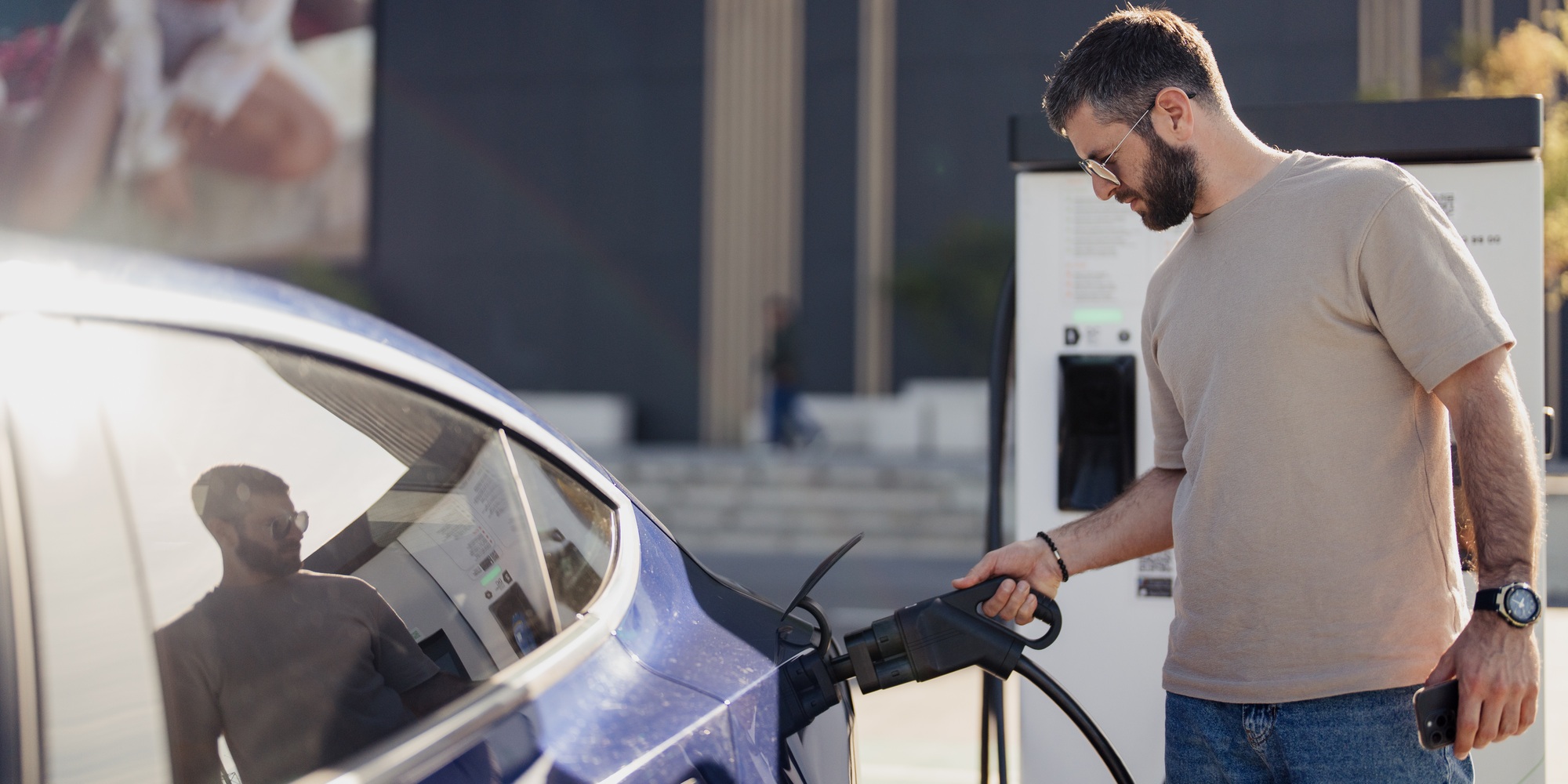 Man charging an electric car at a charging station